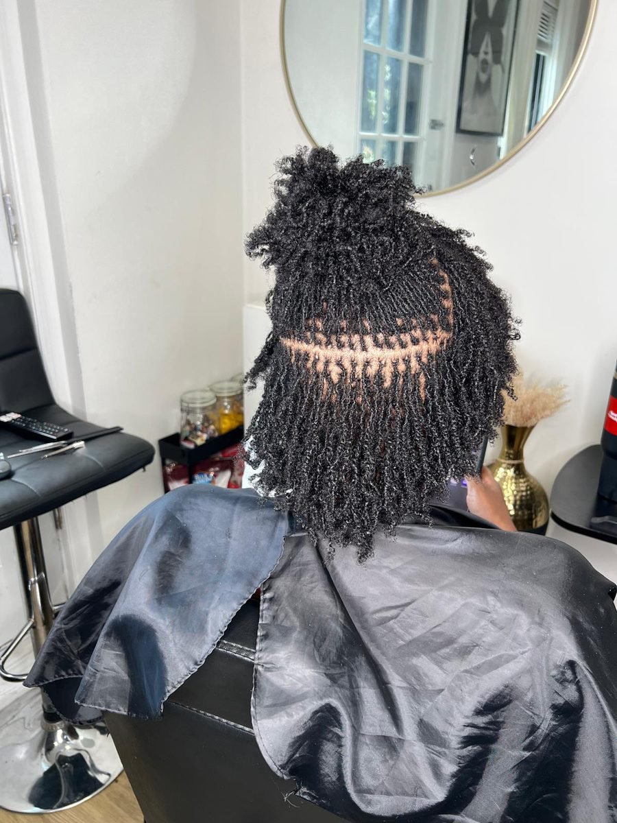 Client with natural two-strand twist updo styled at Locs by Hair Arena