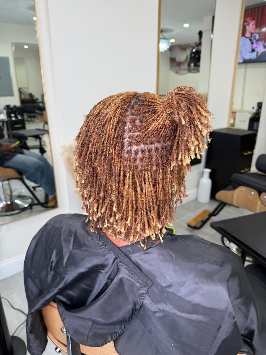 Client with copper colored twist locs styled into a high bun updo
